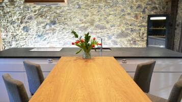 A kitchen with a stone wall, a wooden table, and chairs.