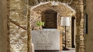 A stone archway leading to a reception desk with a marble counter and a lamp. - Uroczysko Siedmiu Stawów & Spa by L'Occitane (Niemcza)