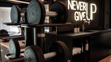 A gym with weightlifting equipment and a motivational sign that reads "NEVER GIVE UP".
