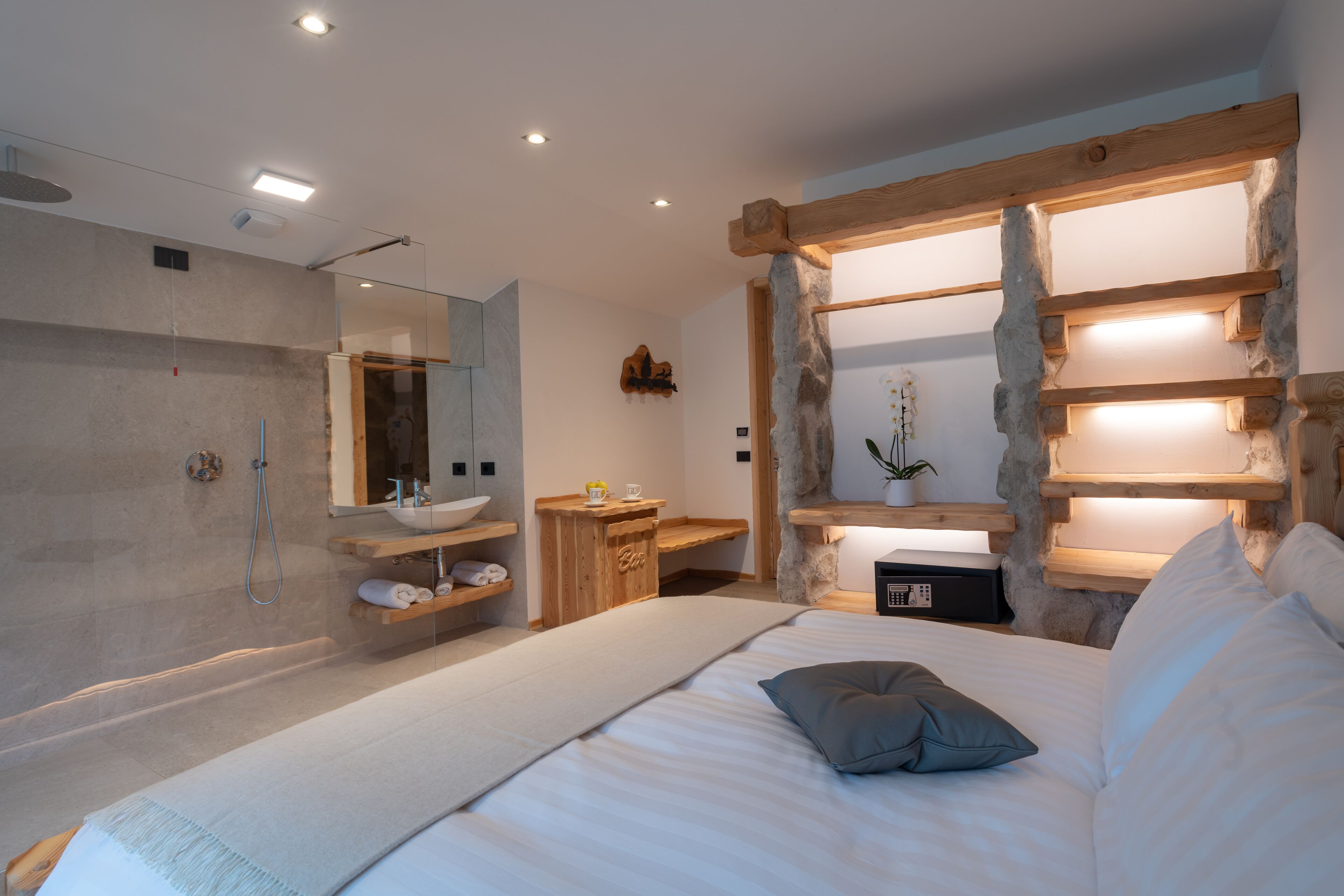 Una camera da letto moderna con un letto grande, una testiera in legno, una mensola a muro, un comodino e uno specchio di grandi dimensioni.