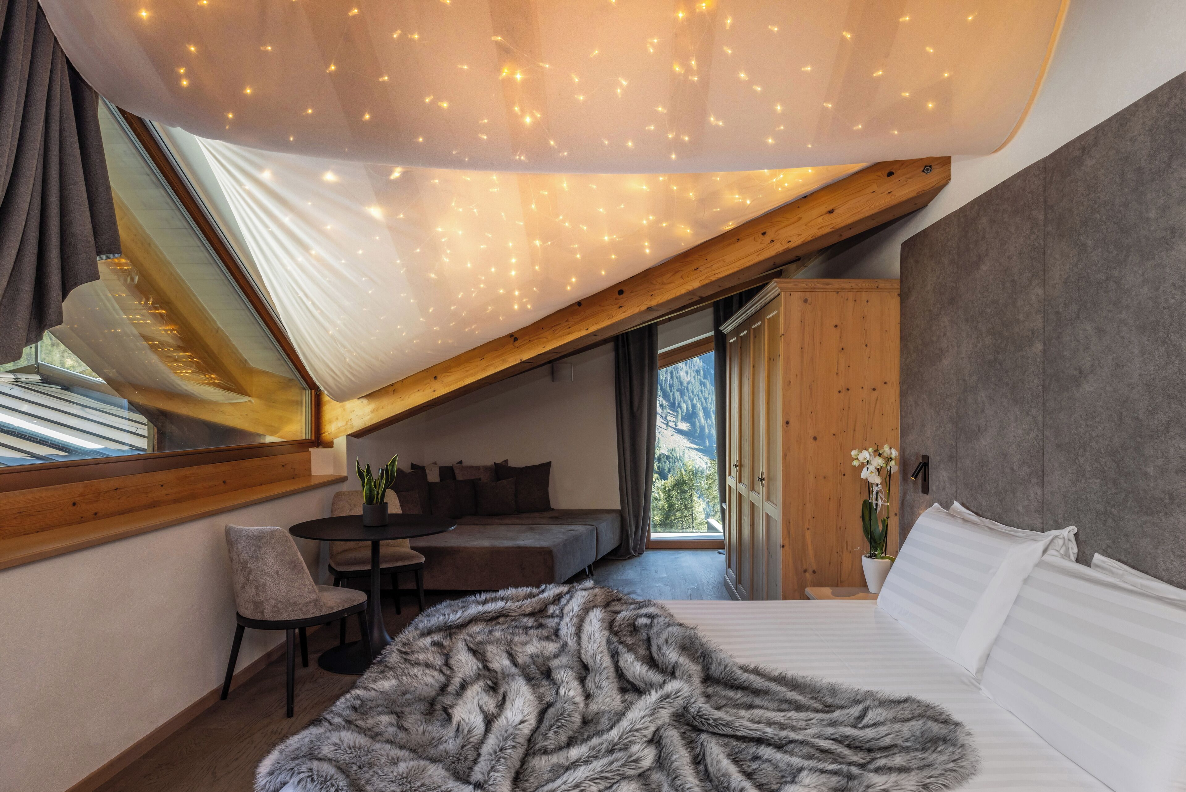 Een slaapkamer met een groot bed, een gezellige zithoek en uitzicht op de omgeving.