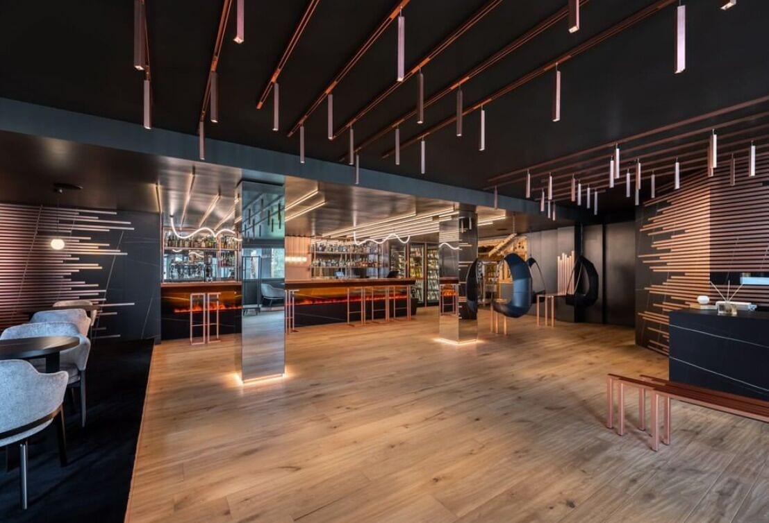 Eine moderne Bar mit Holzboden, Barhocker und Pendelleuchten.