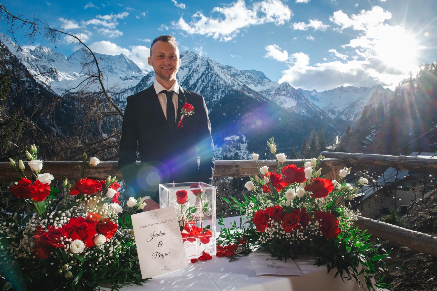 Un homme en costume lors d’une cérémonie de mariage, avec une chaîne de montagnes en arrière-plan.