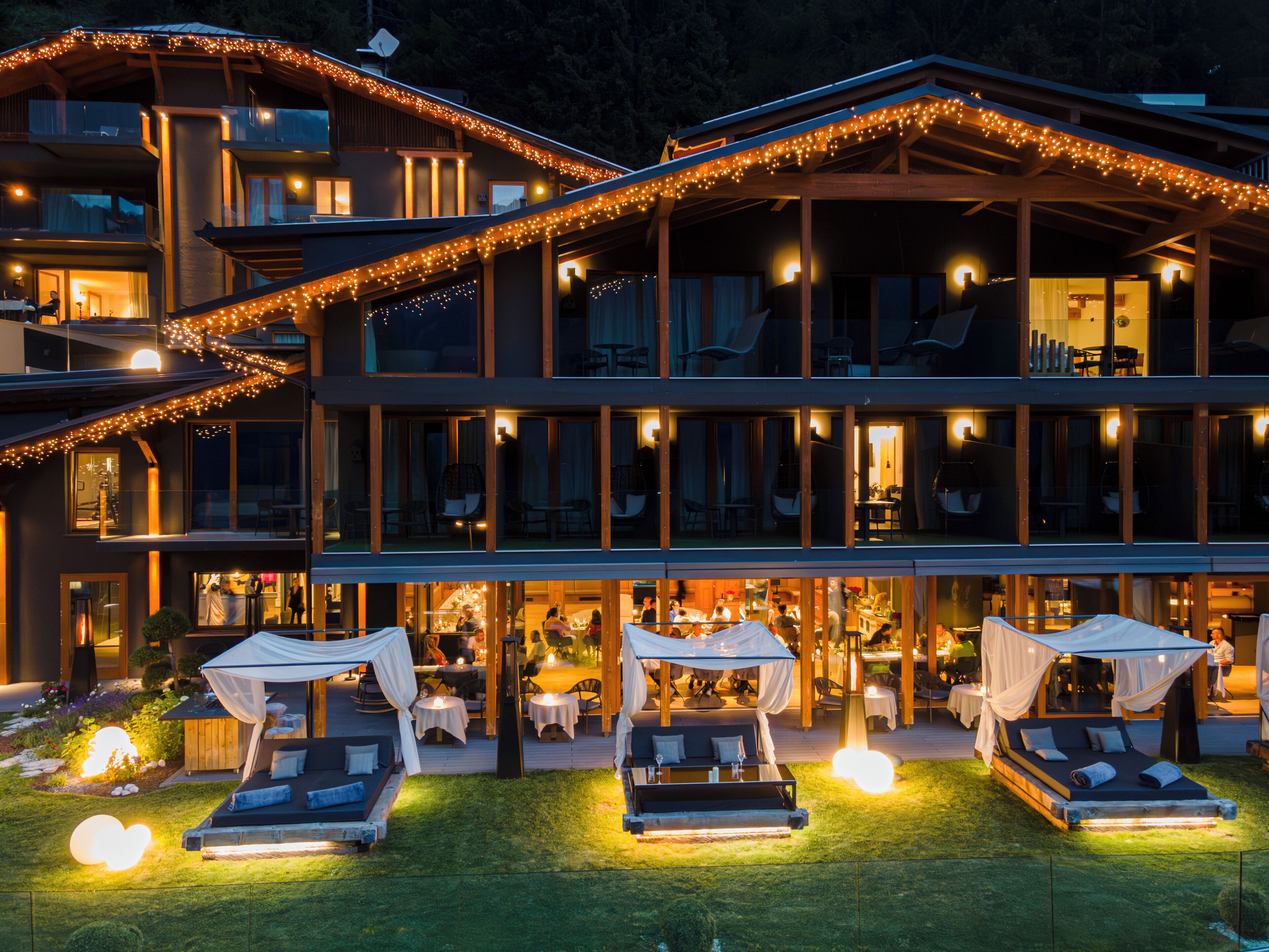 A multi-story hotel with outdoor seating and a well-lit facade.