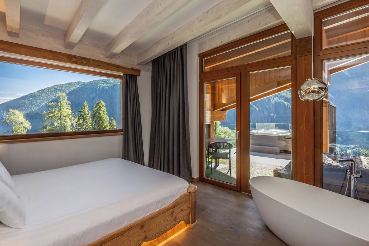 A bedroom with a wooden bed, a large window, and a view of a mountain.