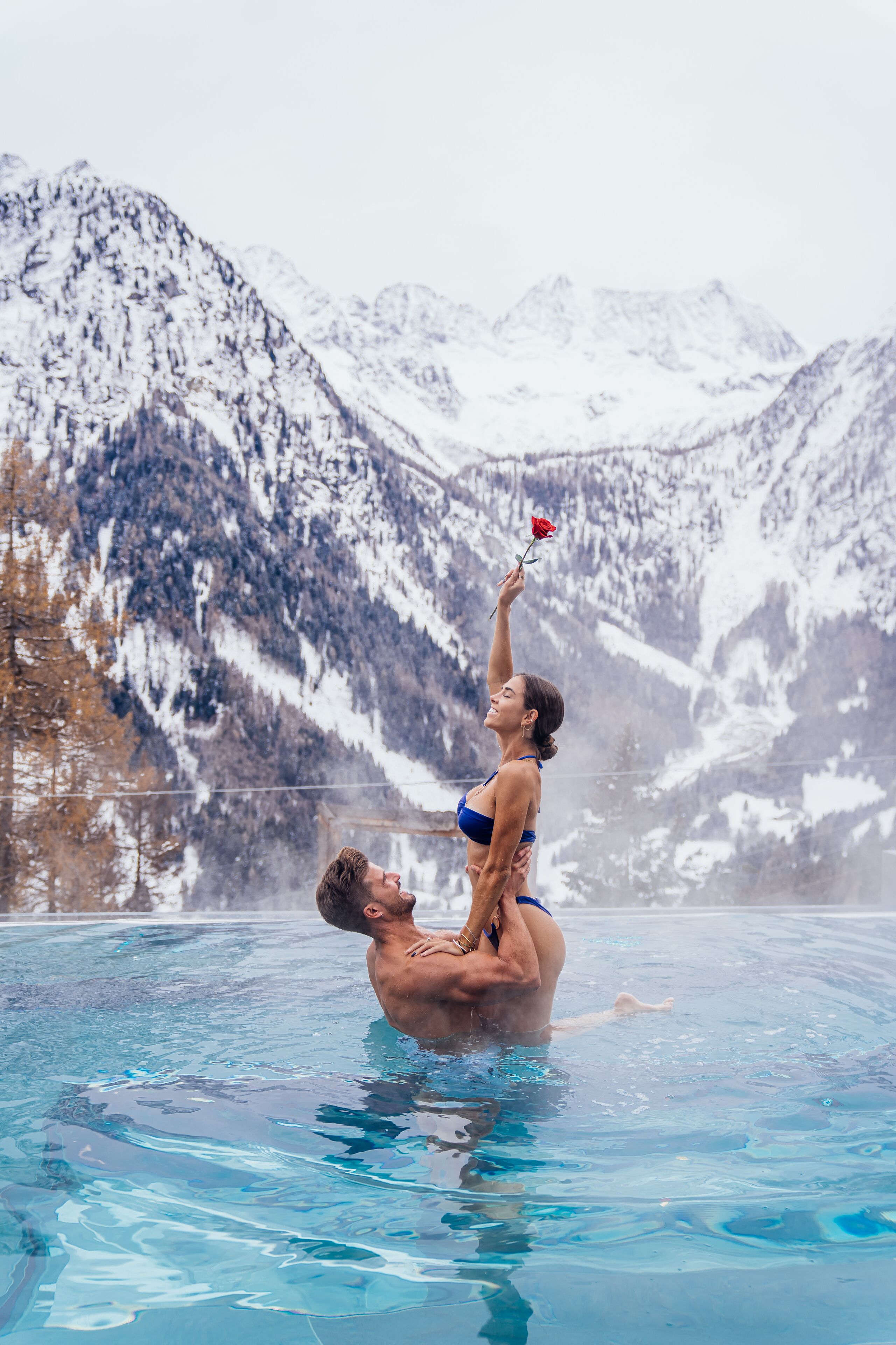 Una coppia in piscina con montagne sullo sfondo.
