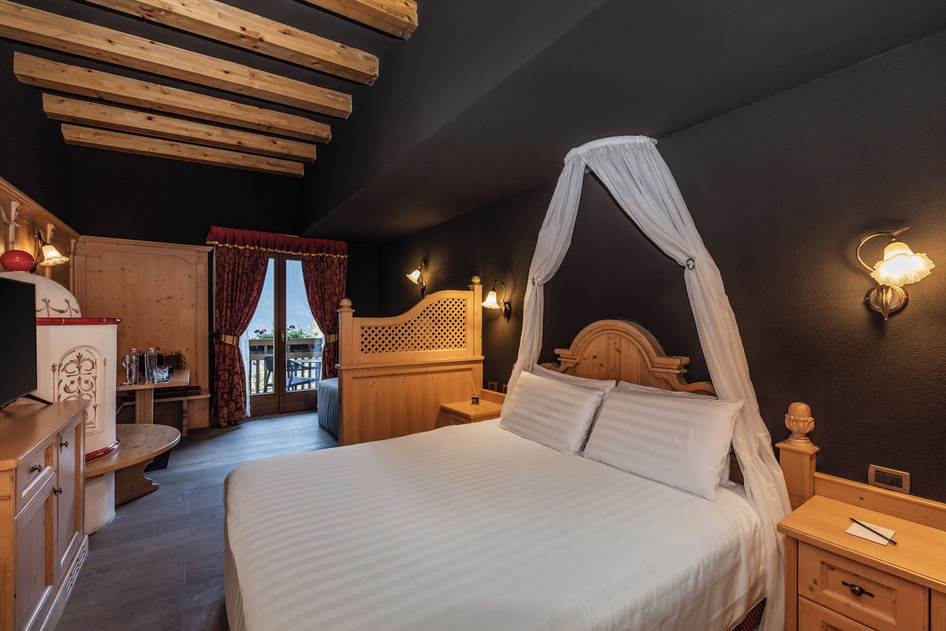 A bedroom with a canopy bed, wooden furniture, and a view of the outside.
