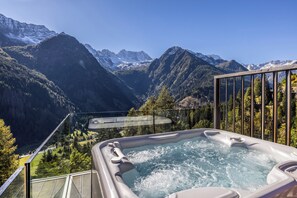 A hot tub with a mountain view, surrounded by a glass railing and a wooden deck. - Hotel Chalet Al Foss (Adults Only) (Vermiglio)