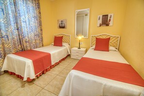 A hotel room with two beds, each with a red and white bedspread, a nightstand with a lamp, and a mirror on the wall. - Ona Sueño Azul (Adeje)