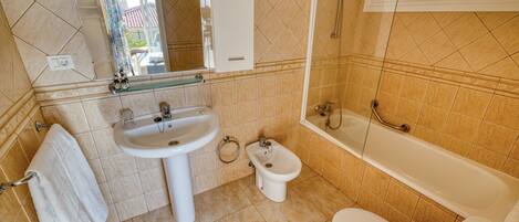 A bathroom with a sink, bidet, toilet, and bathtub.