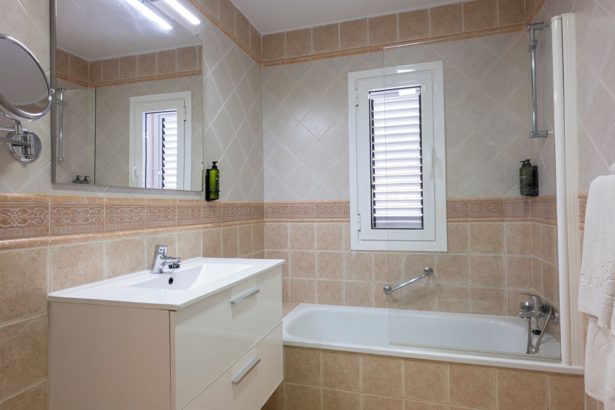 Baño con lavamanos, espejo, ventana y bañera.