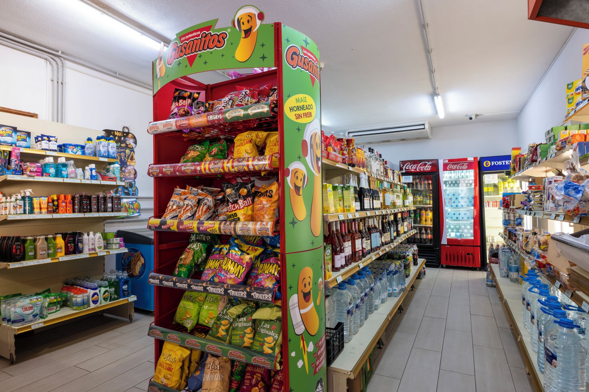 A grocery store aisle with shelves stocked with snacks, beverages, and household items.