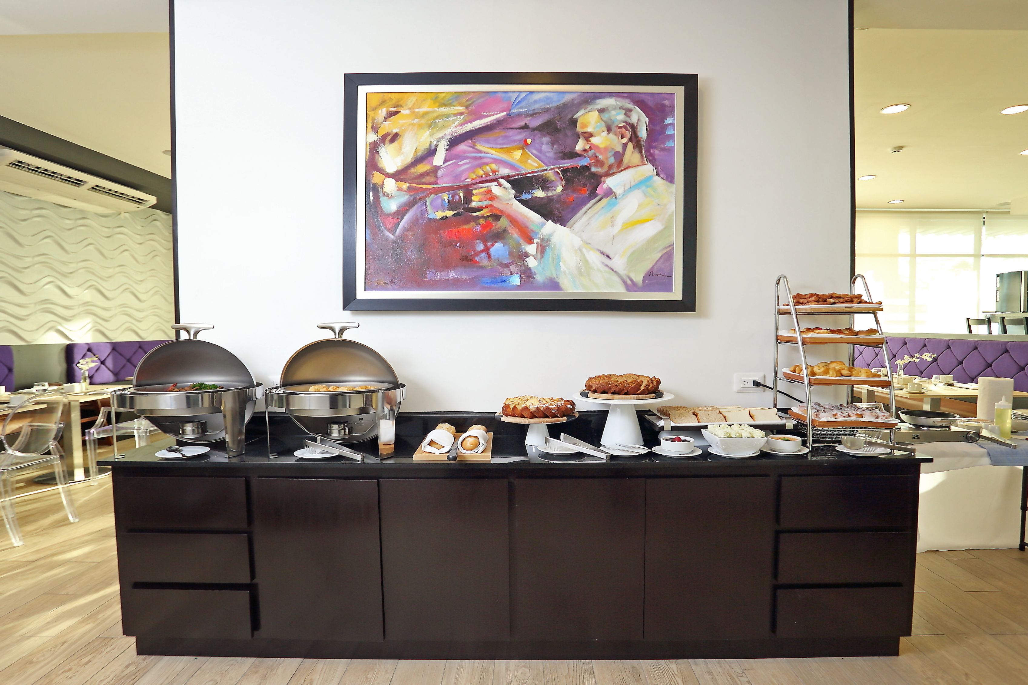 Mesa de buffet con diferentes alimentos y un cuadro en la pared.