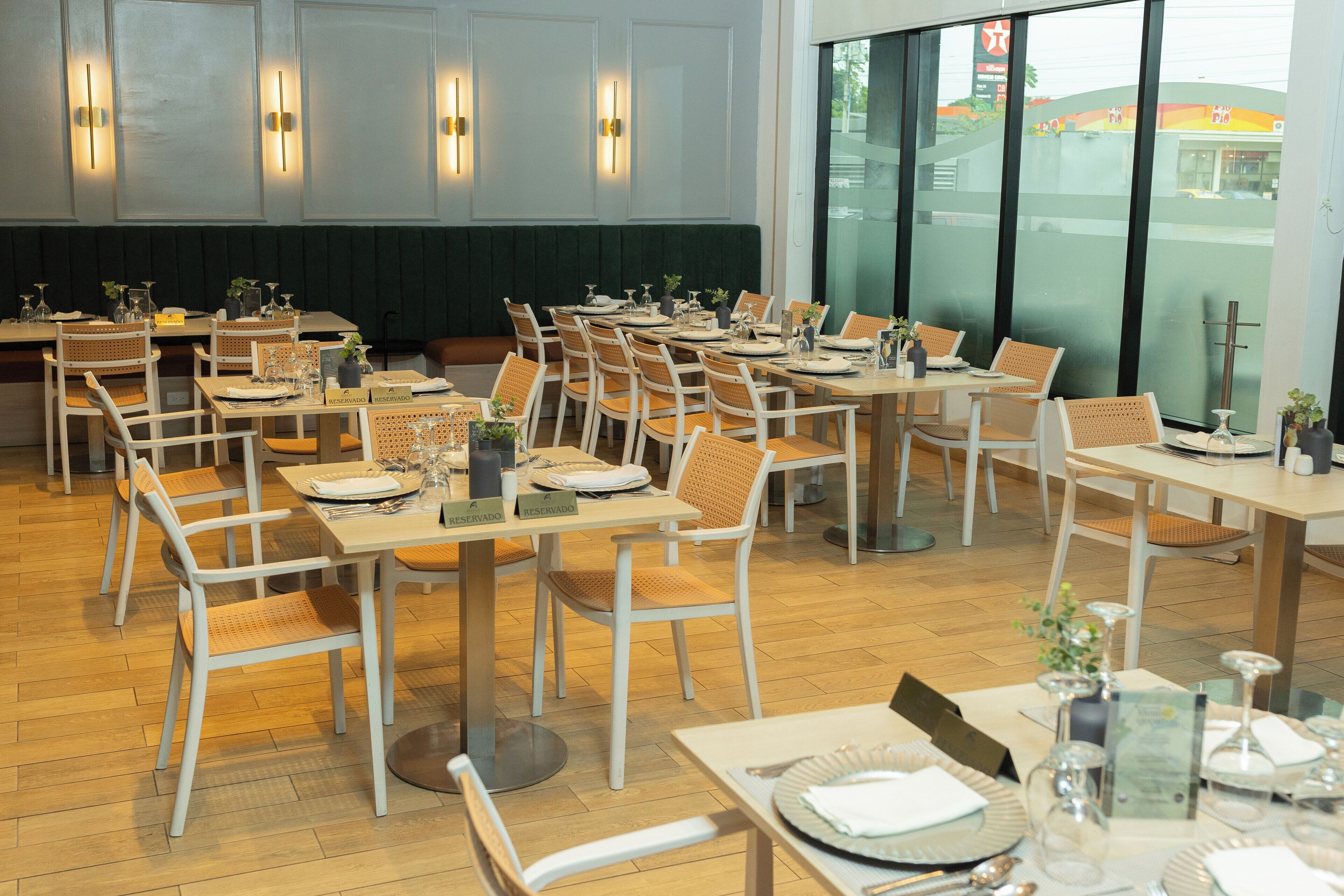 Ein Restaurant mit mehreren Tischen und Stühlen, jeder Tisch ist mit Tellern, Besteck und Gläsern gedeckt.