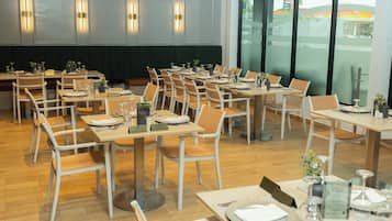 Ein Restaurant mit mehreren Tischen und Stühlen, jeder Tisch ist mit Tellern, Besteck und Gläsern gedeckt.