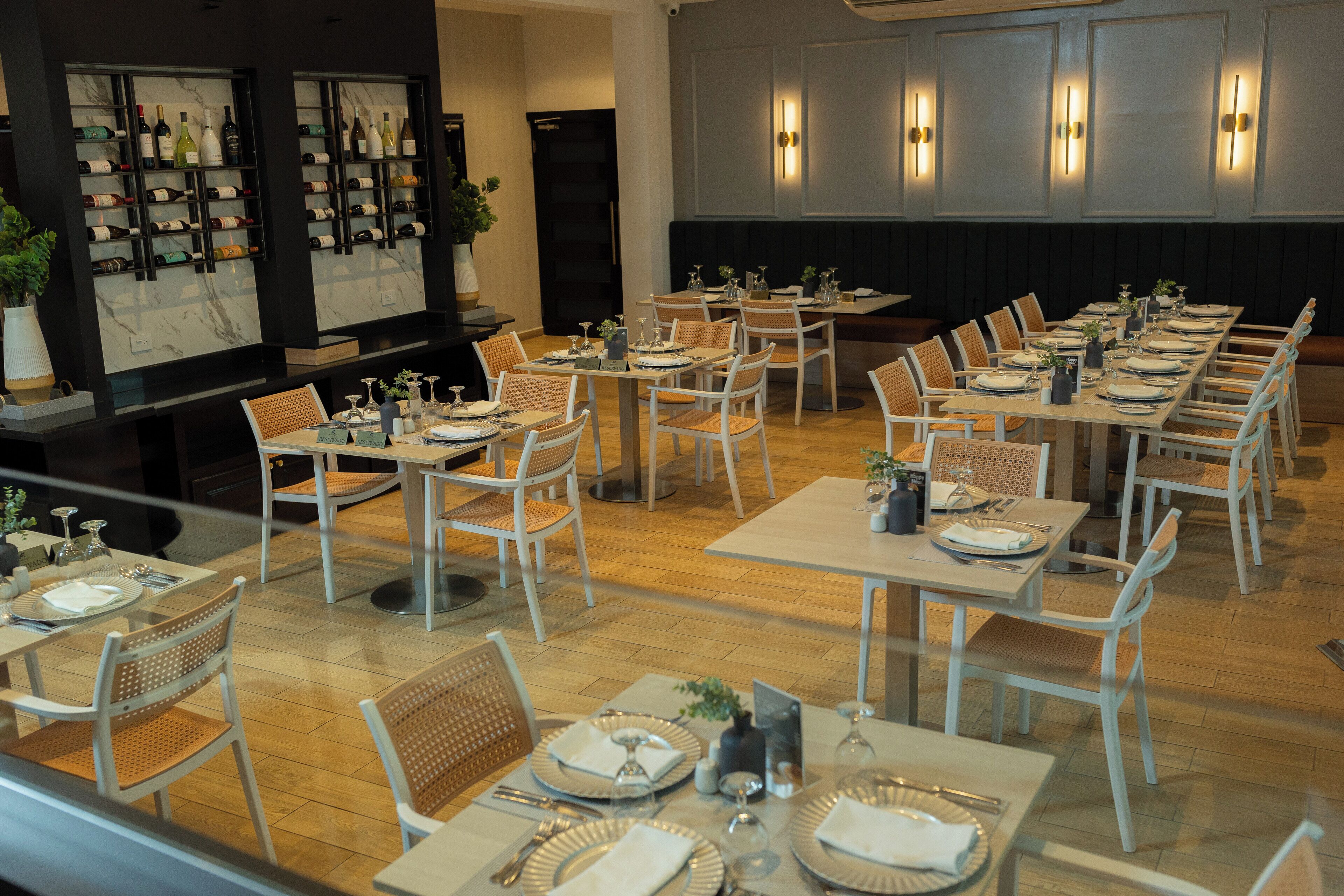 Een restaurant met meerdere tafels klaar voor diners, elk met witte stoelen en netjes gedekte tafels.