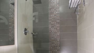 A bathroom with a toilet, a shower with a glass door, and a towel rack.