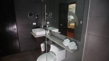 Un baño moderno con inodoro blanco, lavamanos y espejo.