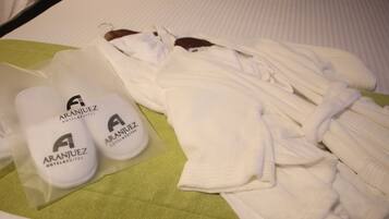 A neatly arranged set of toiletries and a bathrobe on a bed with a green towel.