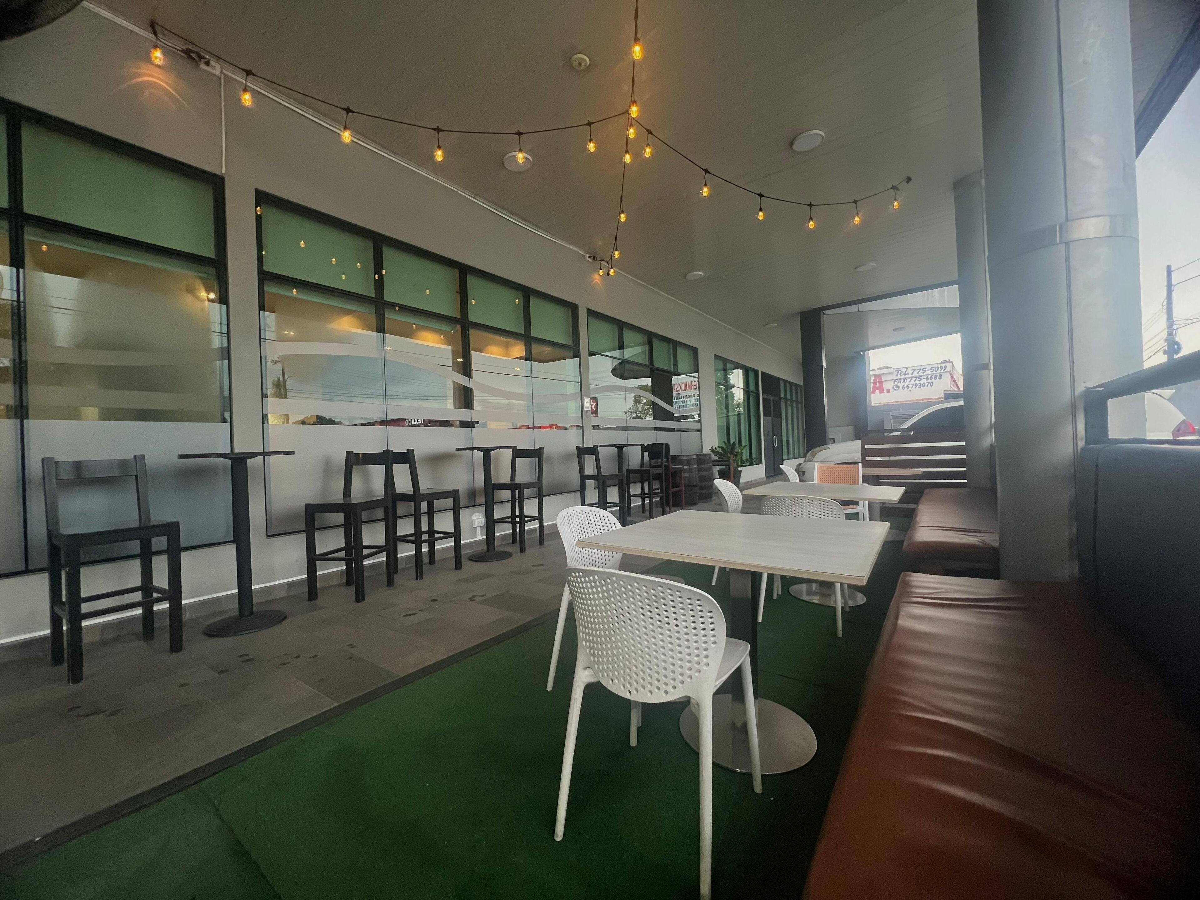 A modern restaurant interior with a green floor, white chairs, and tables.