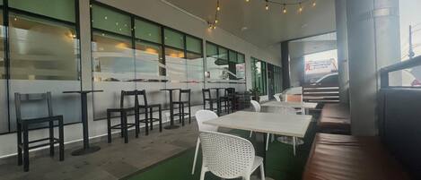 A modern restaurant interior with a green floor, white chairs, and tables.