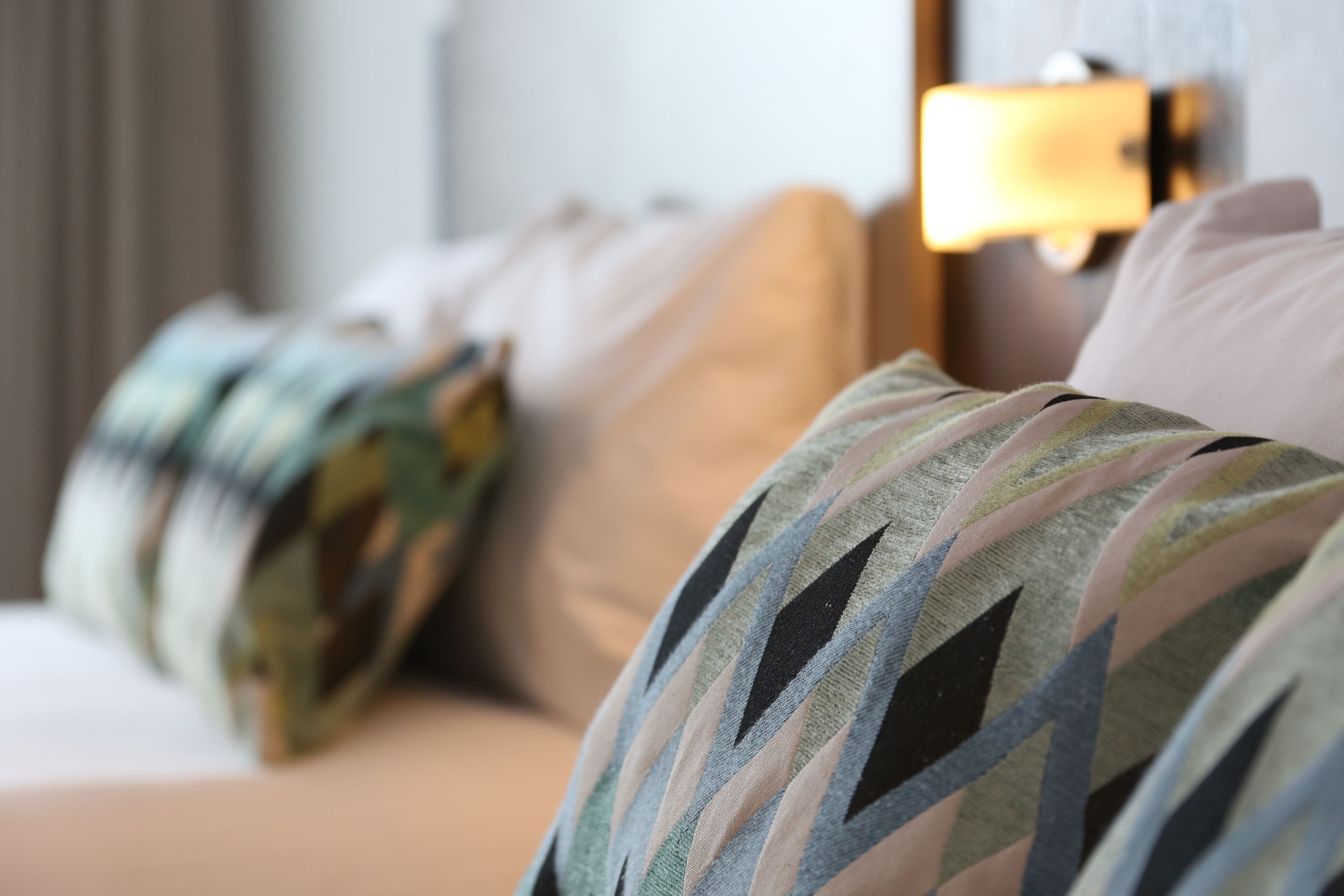 Une chambre d’hôtel avec un lit agrémenté d’oreillers à rayures et d’une lampe de chevet.
