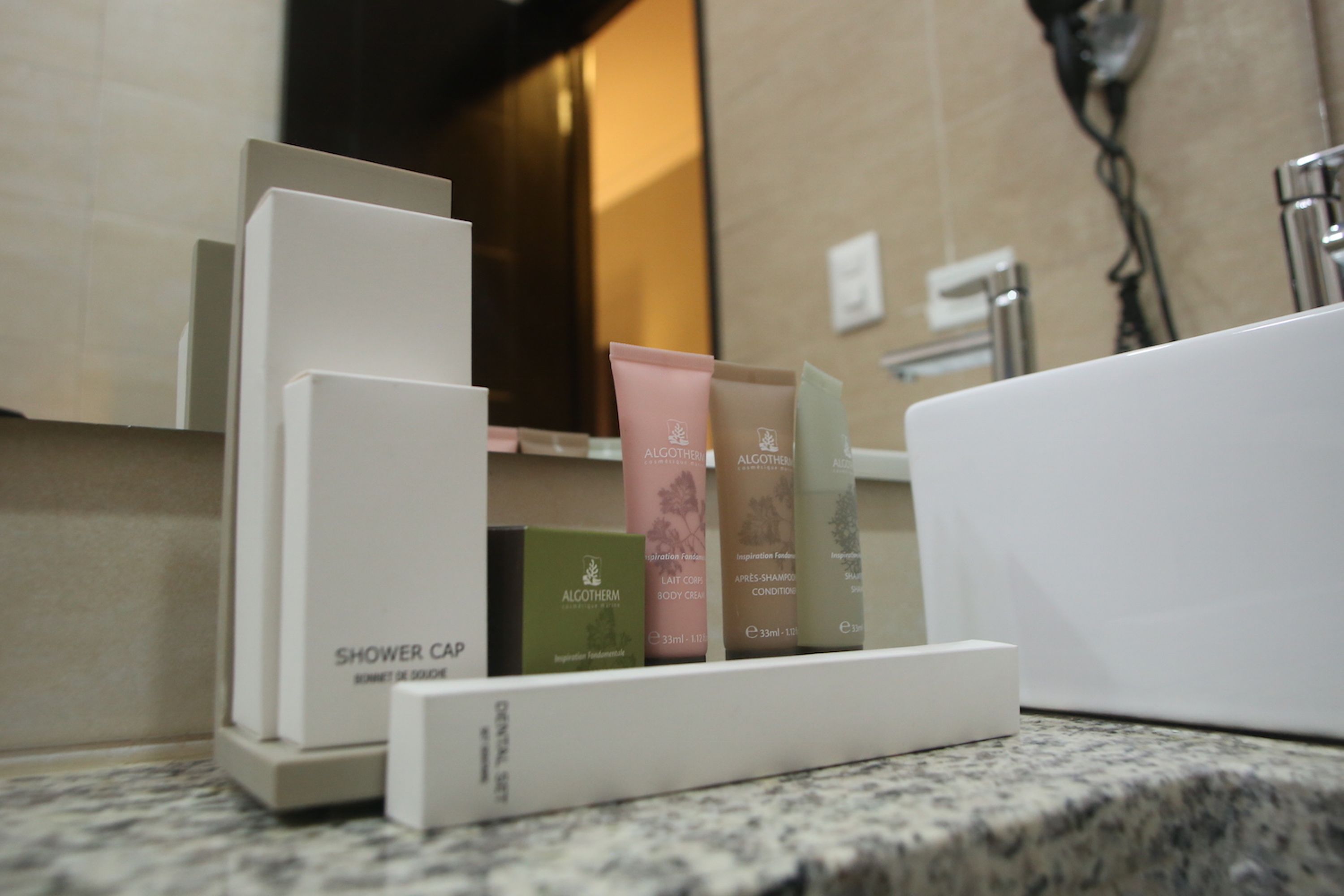 A shower area with a soap dispenser and a bottle of shower gel.