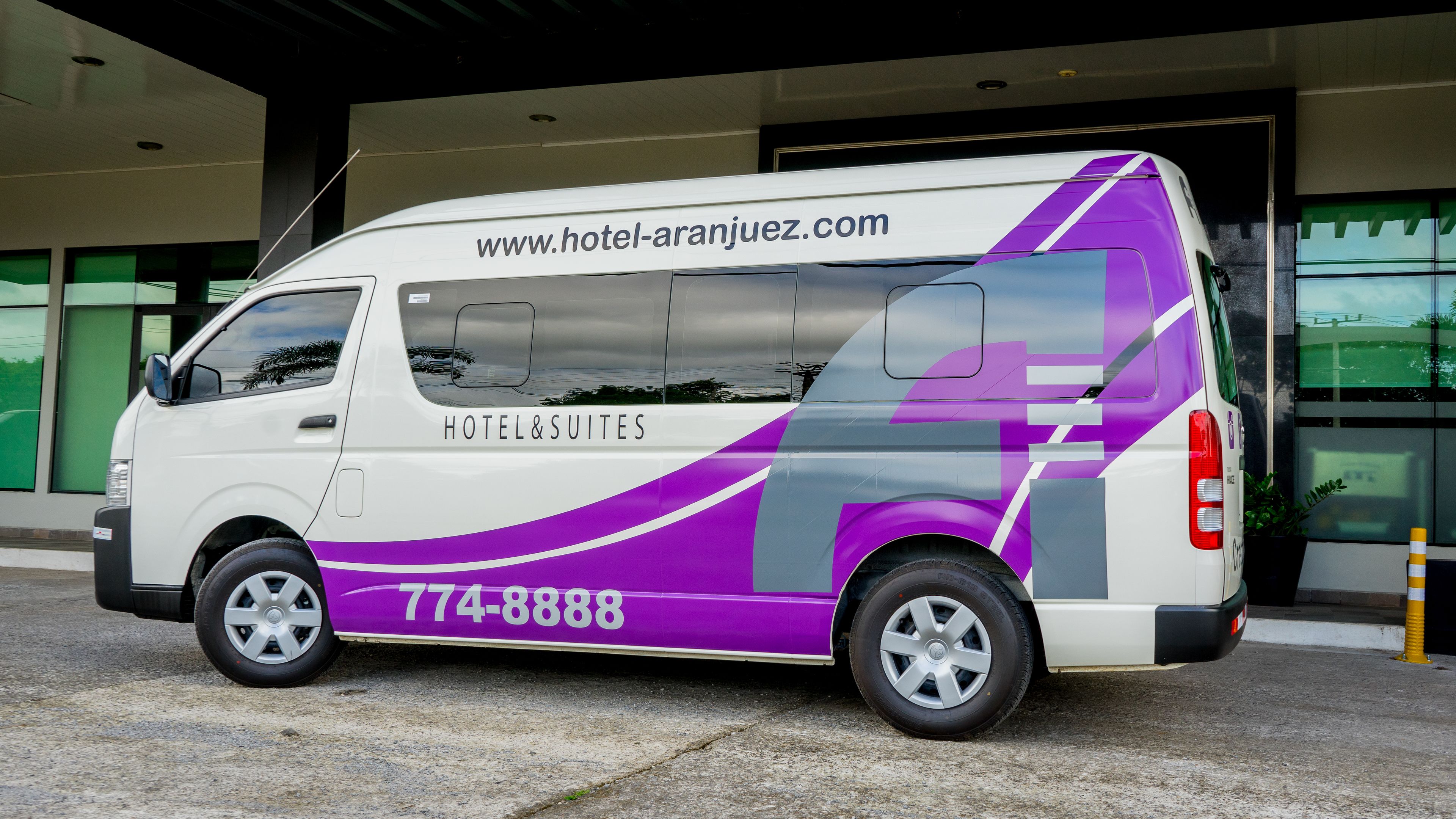 A white and purple van with the text "HOTEL&SUITES" and a phone number.