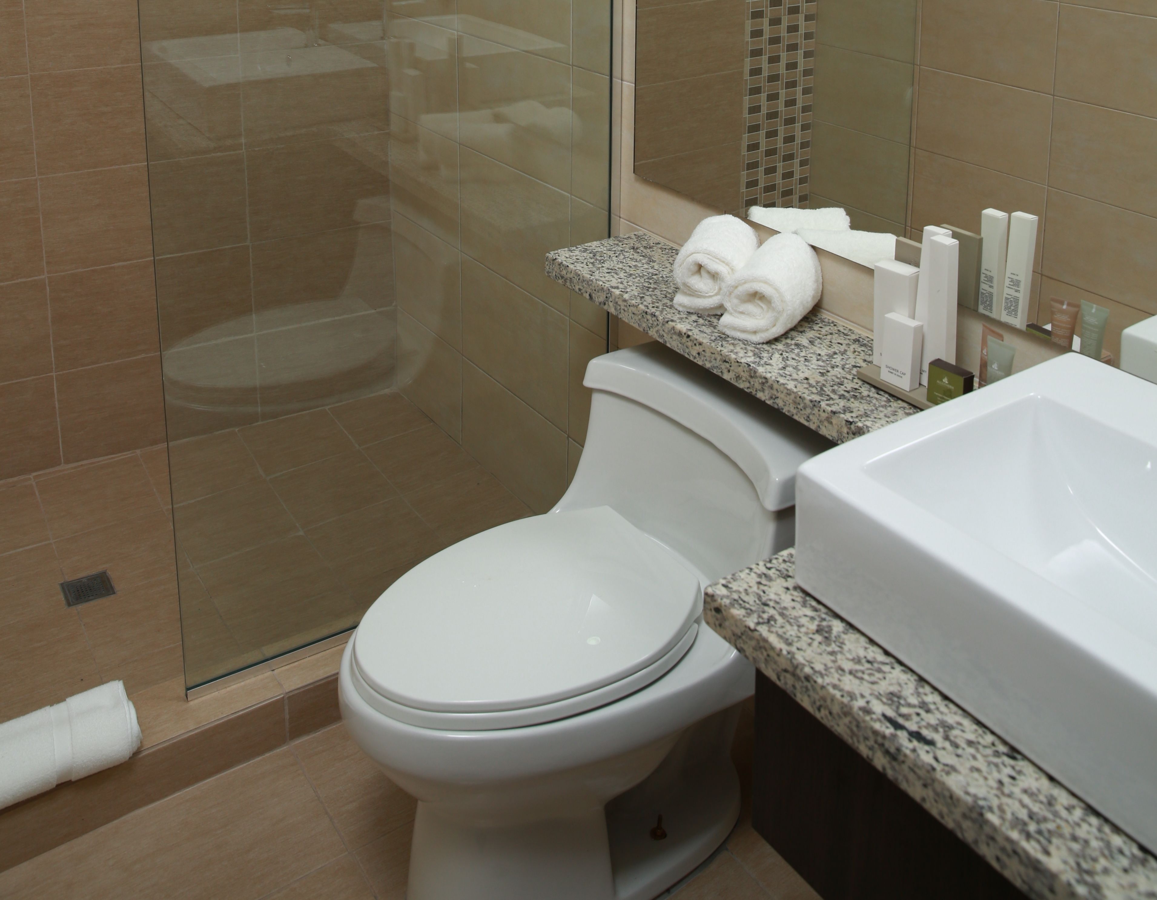 A modern bathroom with a toilet, shower, and sink.