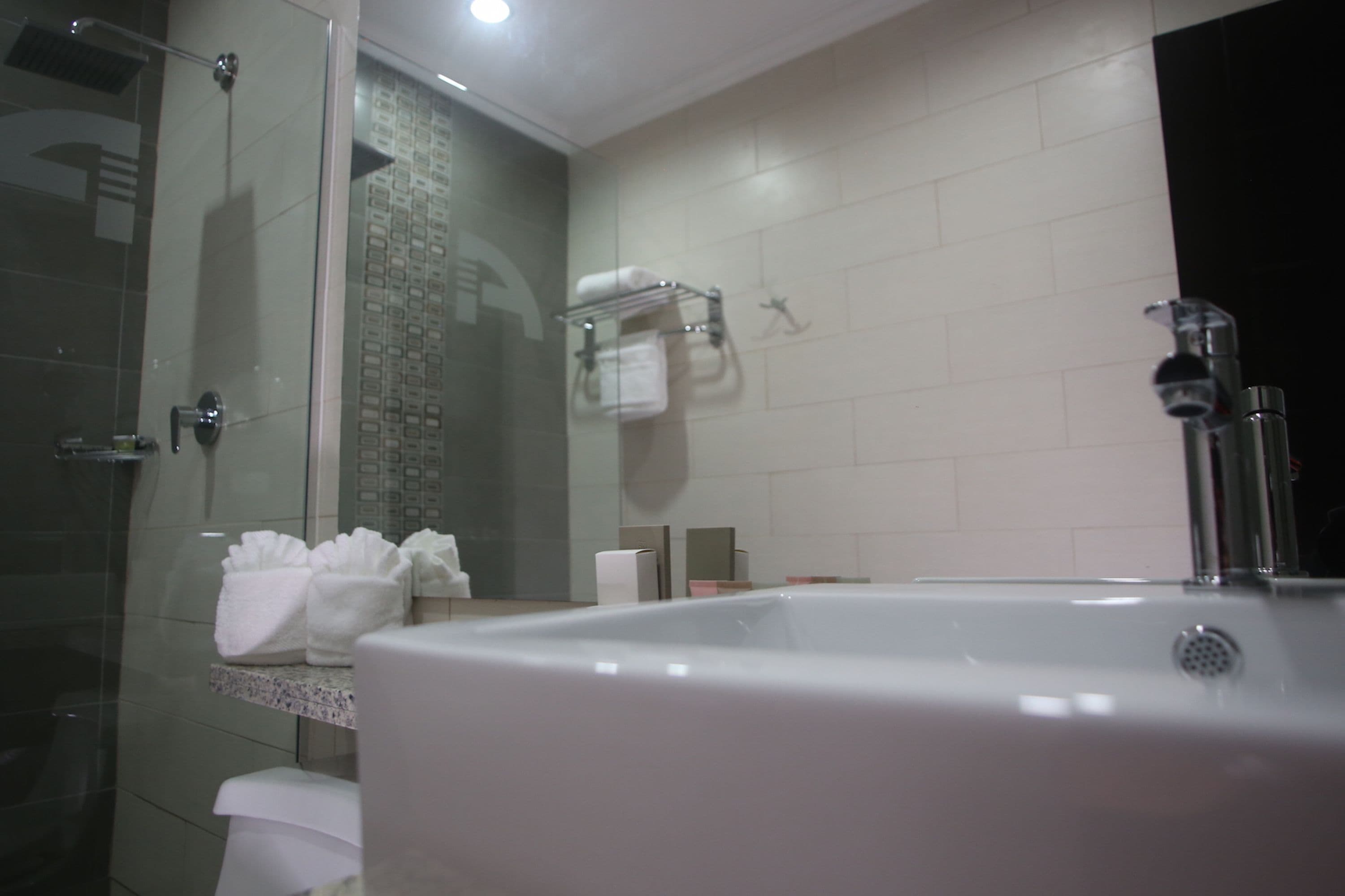 A modern bathroom with a glass-enclosed shower, a large bathtub, and a towel rack with folded towels.