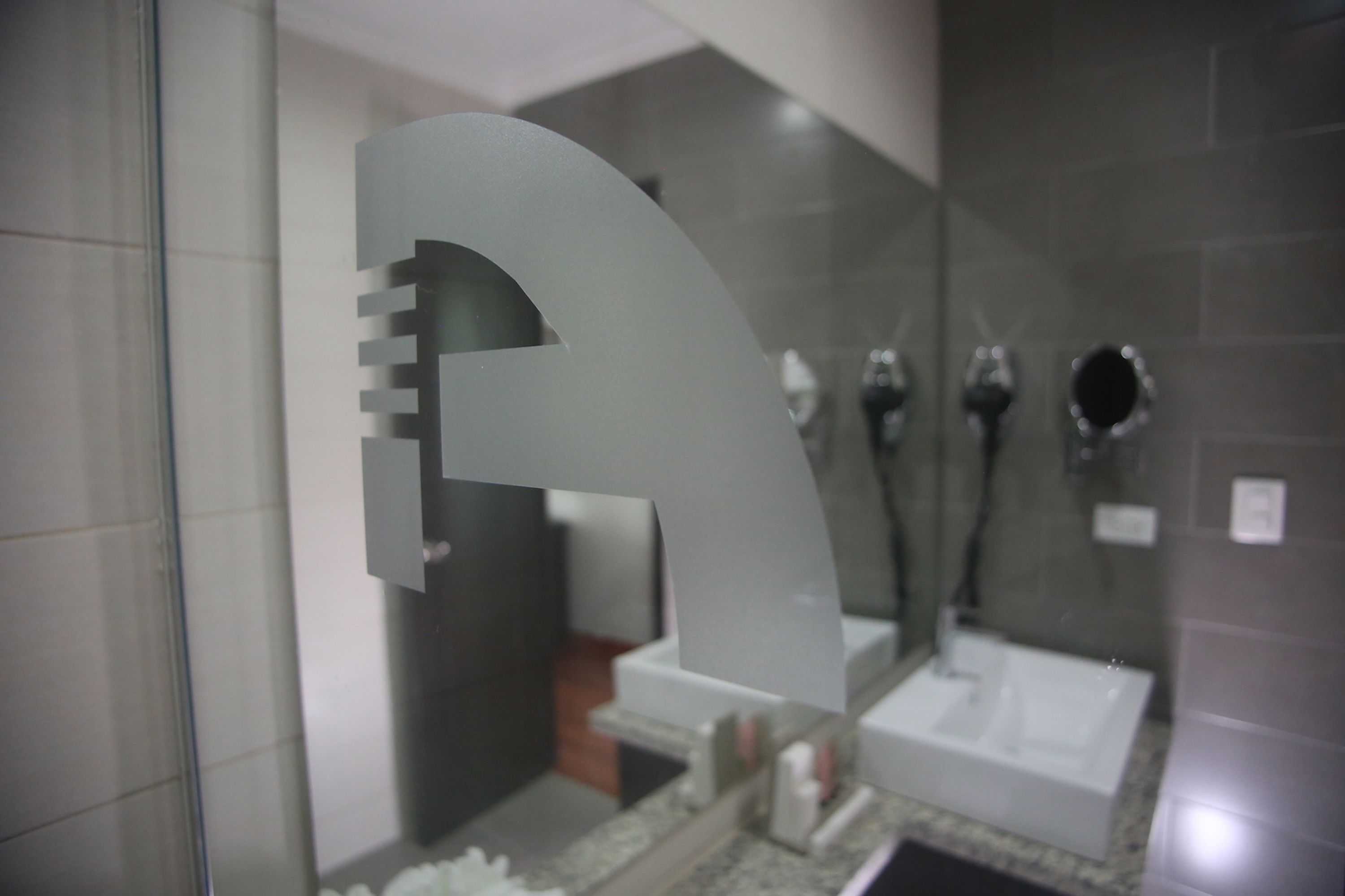 Un baño moderno con un espejo grande, un lavabo y una zona de ducha.