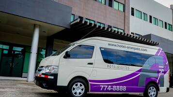 Ein weißer und violetter Van parkt vor einem Hotel, auf dessen Seite die Website www.hotel-aranjuez.com und die Nummer 774-8888 zu sehen sind.