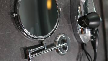 A bathroom mirror with a chrome frame and a hairdryer mounted on the wall.