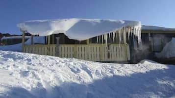 A snow-covered porch with icicles hanging from the roof.