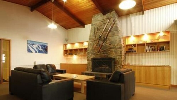 Una sala de estar acogedora con chimenea de piedra, sofás de cuero y una estantería.