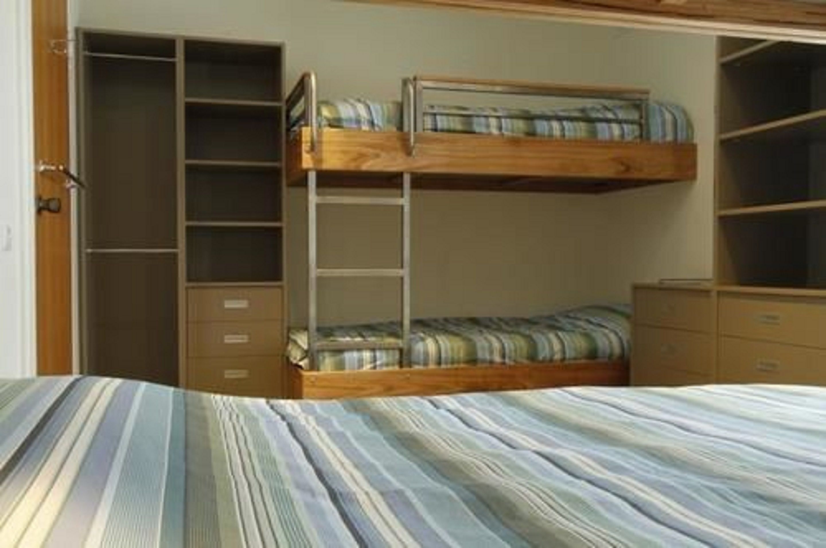 A bunk bed room with a wardrobe and a desk.