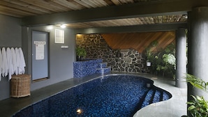 A swimming pool with mosaic tiles, a stone wall, and a wooden ceiling. - Falls Creek Hotel (Falls Creek)