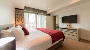 Habitación de hotel moderna con una cama grande, televisión de pantalla plana, escritorio y ventana con cortinas.