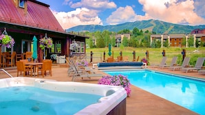 Un espace piscine doté d’un jacuzzi, de chaises longues et offrant une vue sur les montagnes.