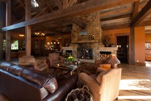 A spacious living area with a stone fireplace, leather sofas, and a wooden ceiling. - The Porches of Steamboat Springs (Steamboat Springs)