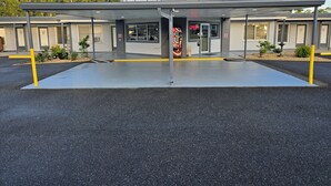 A building with a covered entrance, a parking lot, and a vending machine.