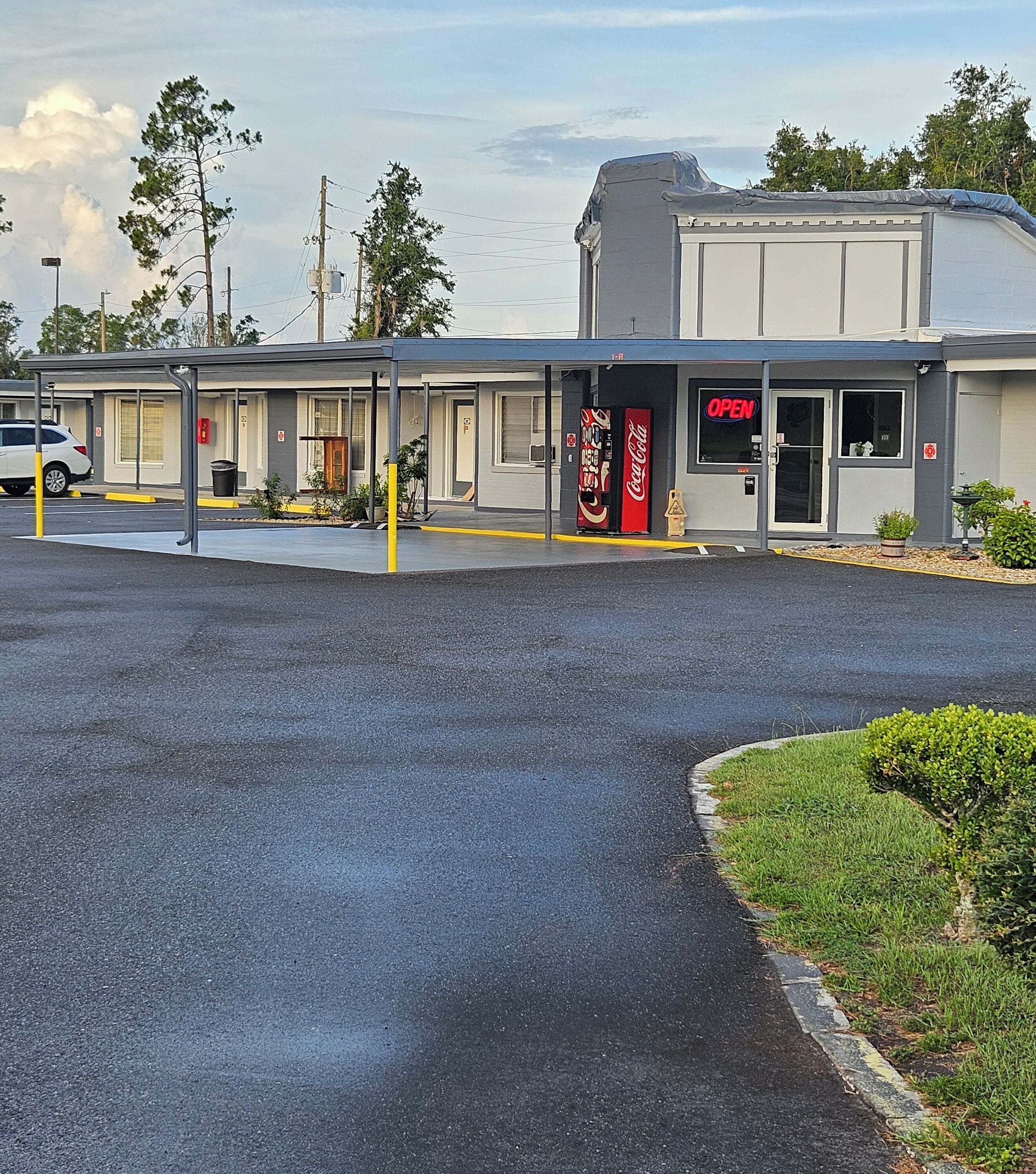 Un motel avec une enseigne Coca-Cola, un parking et un bâtiment portant le numéro « 1-1 ».