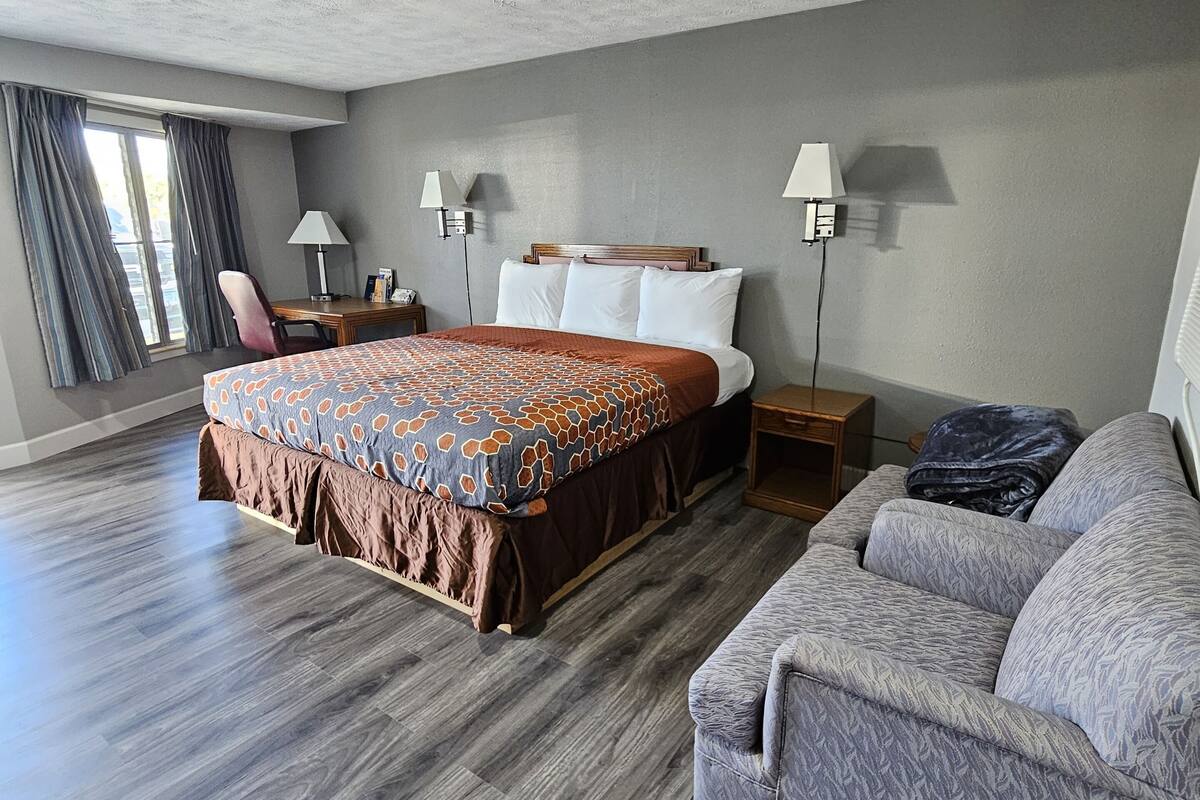 Une chambre d’hôtel avec un grand lit, un canapé, un bureau et une lampe.