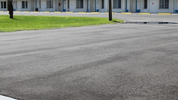A motel with a row of rooms, a grassy area, and a wet parking lot.