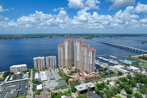 A high-rise hotel with multiple floors, a marina with boats, and a bridge in the background. - The Hibiscus House  (Fort Myers)