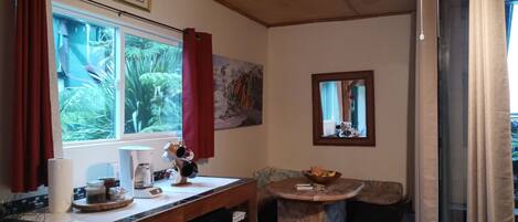 A compact kitchen with a window, a microwave, a coffee maker, and a small refrigerator.