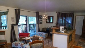 A cozy living room with a sofa, chairs, a coffee table, and a kitchen area with a coffee maker. - Aloha Crater Lodge (Volcano)