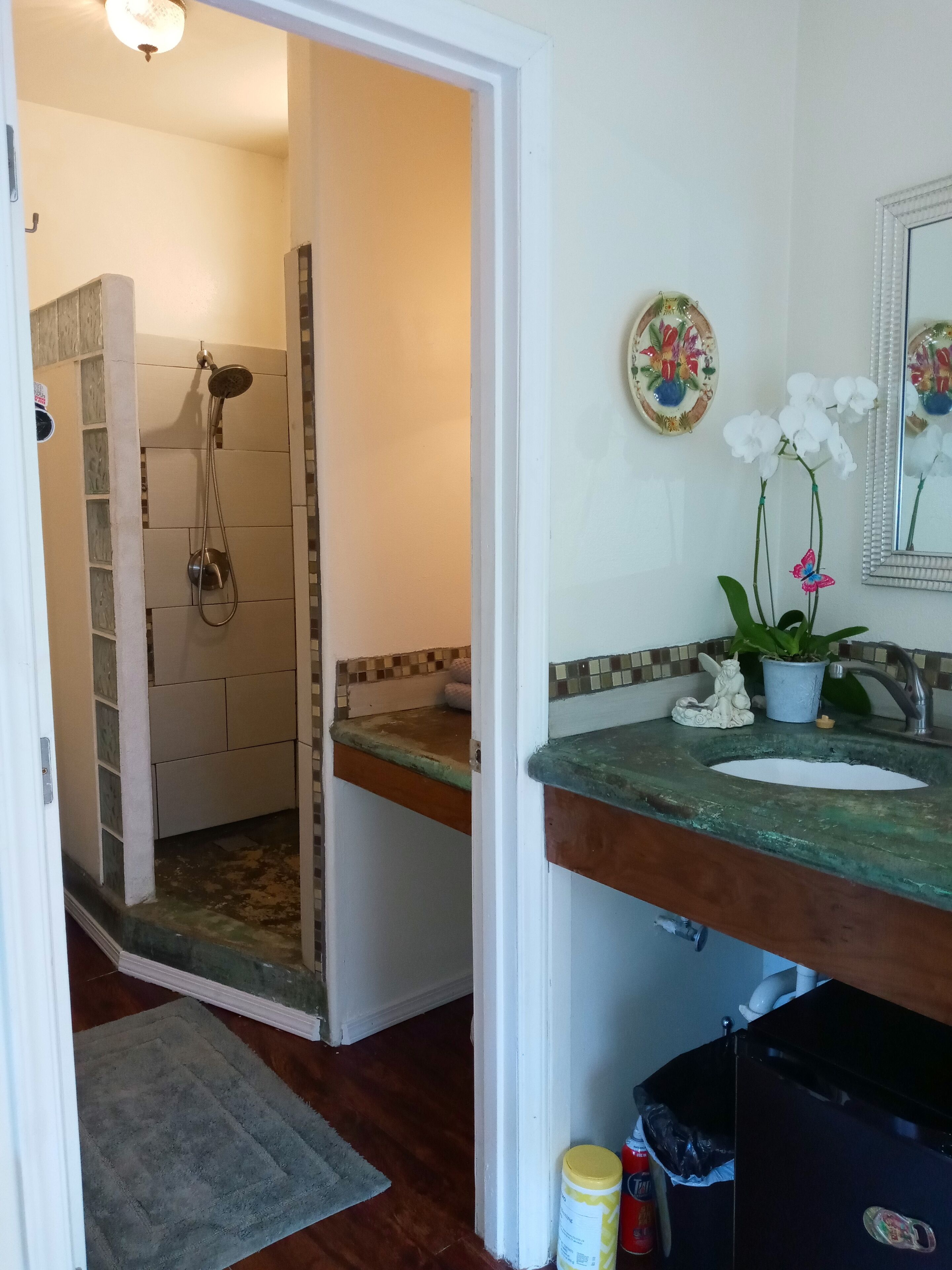 Un baño con ducha, lavamanos, placas decorativas y un espejo.