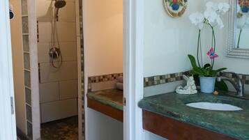 Un baño con ducha, lavamanos, placas decorativas y un espejo.