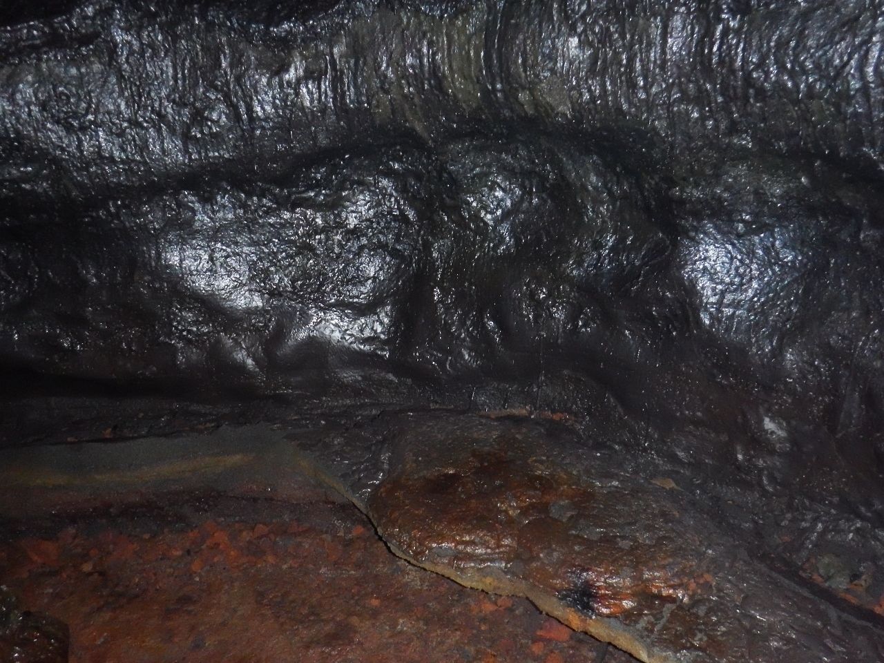 Interno di una grotta con pareti irregolari e pavimento bagnato.